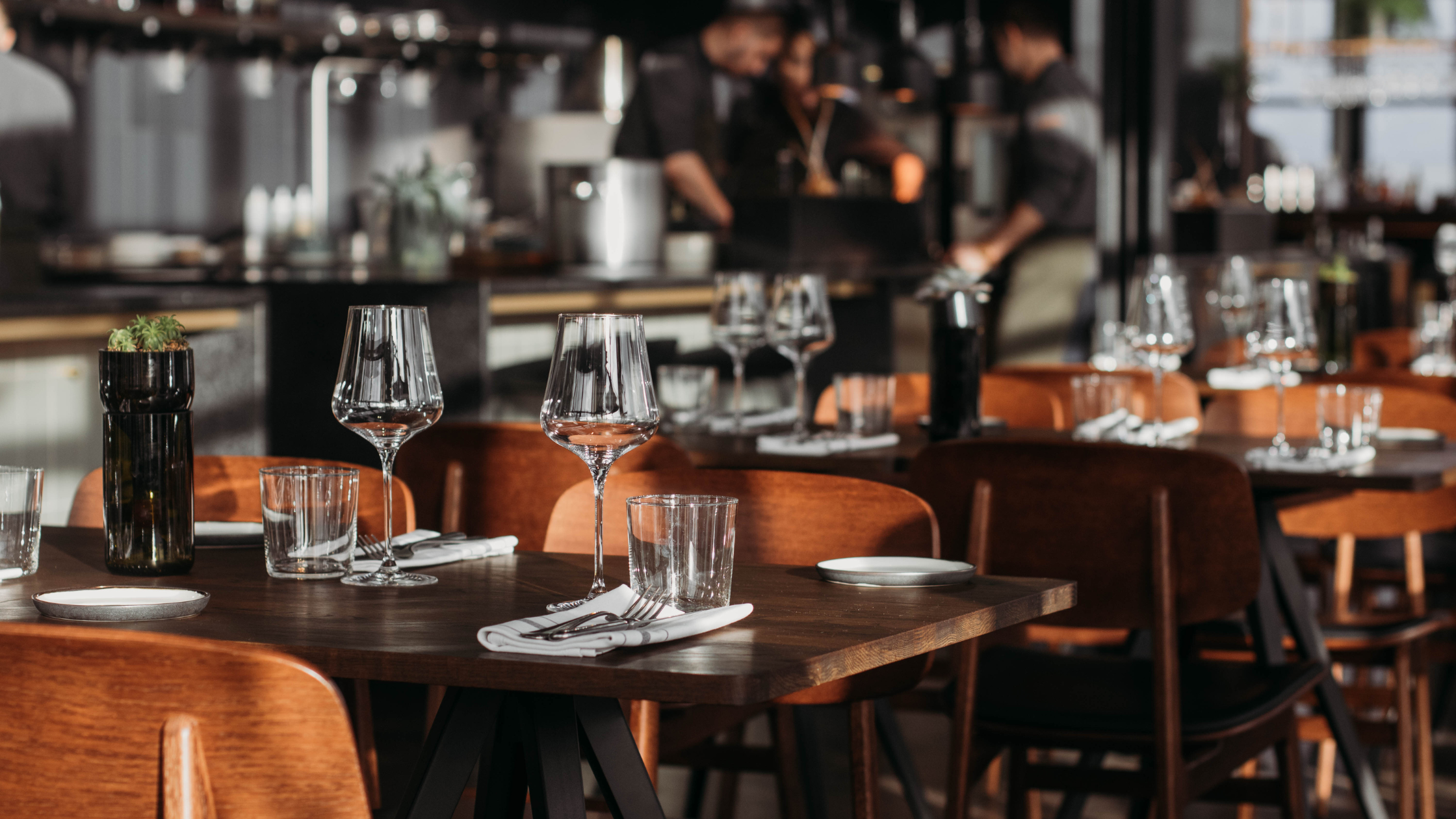 Sala elegante de restaurante con mesas preparadas y sillas naranjas, lista para recibir comensales.